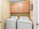 Laundry room with overhead storage and standard size washer and dryer at 16802 Fairbolt Way, Odessa, FL 33556