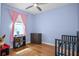 Cozy bedroom with hardwood floors, ceiling fan, pink curtains, and crib at 1755 Open Field Loop, Brandon, FL 33510
