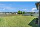 Backyard with lush green grass, a white fence, and a tranquil pond view at 21003 Monza Loop, Land O Lakes, FL 34638