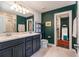 Bathroom featuring a double vanity, tiled floors, a large mirror, and green accent wall at 21003 Monza Loop, Land O Lakes, FL 34638