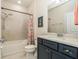 Well-lit bathroom featuring a tub with shower, dark vanity, and clean white tiling at 21003 Monza Loop, Land O Lakes, FL 34638