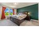 Bedroom with a large bed with dark wood frame, bedside tables, and a green accent wall at 21003 Monza Loop, Land O Lakes, FL 34638