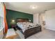 Bedroom with a large bed with dark wood frame, bedside tables, and a green accent wall at 21003 Monza Loop, Land O Lakes, FL 34638
