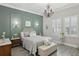 Serene bedroom with soft green walls, a chandelier, plantation shutters, and stylish furnishings at 21746 Amelia Rose Way, Land O Lakes, FL 34637