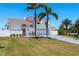 A two-story home with a white exterior, red roof, two-car garage, palm trees, and a green lawn at 2202 Donato Dr, Belleair Beach, FL 33786