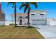Two-story home boasts a white exterior, red roof, two-car garage, and two palm trees in the front yard at 2202 Donato Dr, Belleair Beach, FL 33786