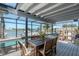 Covered patio with dining table and chairs overlooking serene water views and waterfront landscaping at 2202 Donato Dr, Belleair Beach, FL 33786