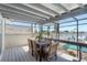 Relaxing screened-in porch features a dining area with scenic views of the pool and waterfront at 2202 Donato Dr, Belleair Beach, FL 33786