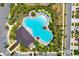 Birds eye view of a community pool with light blue water, green umbrellas, and verdant landscaping at 3078 Marine Grass Dr, Wimauma, FL 33598