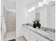 Bright bathroom featuring double sinks with granite countertops and a tiled walk-in shower for modern living at 3078 Marine Grass Dr, Wimauma, FL 33598