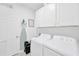 Well-equipped laundry room with a washer, dryer, ample cabinet space, and ironing board for convenience at 3078 Marine Grass Dr, Wimauma, FL 33598