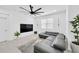 Bright living room featuring a modern ceiling fan, sleek sectional sofa, and entertainment center at 3078 Marine Grass Dr, Wimauma, FL 33598
