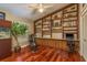 Well-lit home office featuring hardwood floors, custom bookshelves, and a large window with a view at 3138 Edgemoor Dr, Palm Harbor, FL 34685