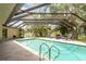 Enclosed pool area features an in-ground pool, tiled deck, screened enclosure, and cozy outdoor seating at 3138 Edgemoor Dr, Palm Harbor, FL 34685