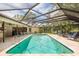 The screened-in pool area features a sparkling pool, lounge chairs and views of the lake, creating a serene outdoor oasis at 3138 Edgemoor Dr, Palm Harbor, FL 34685