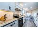 Well-lit kitchen with sleek appliances, marble counters, white cabinetry and wood-look floors at 382 Tavernier Cir, Oldsmar, FL 34677