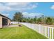 Expansive backyard featuring lush green grass, screened lanai, and a stylish white picket fence at 3914 Round Table Ct, Land O Lakes, FL 34638