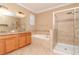 Luxurious bathroom featuring double sinks, a soaking tub, a tiled shower, and granite countertops at 3914 Round Table Ct, Land O Lakes, FL 34638