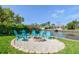 Backyard view of outdoor firepit surrounded by blue Adirondack chairs overlooking a canal and dock at 3922 Fontainebleau Dr, Tampa, FL 33634