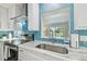 Stylish kitchen featuring a stainless steel sink, marble countertops, and a unique blue geometric backsplash at 3922 Fontainebleau Dr, Tampa, FL 33634