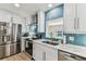 Modern kitchen featuring white cabinets, marble countertops, stainless steel appliances, and blue geometric backsplash at 3922 Fontainebleau Dr, Tampa, FL 33634