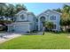 Charming two-story home with lush green lawn, landscaped yard, and a light blue exterior at 4063 Ligustrum Dr, Palm Harbor, FL 34685