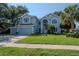 Charming two-story home with lush green lawn, landscaped yard, and a light blue exterior at 4063 Ligustrum Dr, Palm Harbor, FL 34685