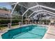 View of the screened-in pool area with a waterfall feature and lush landscaping at 4063 Ligustrum Dr, Palm Harbor, FL 34685