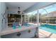 Outdoor bar with two barstools and screened in pool area with outdoor seating at 4063 Ligustrum Dr, Palm Harbor, FL 34685