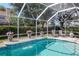Screened-in pool area with a clear blue swimming pool and patio furniture at 4063 Ligustrum Dr, Palm Harbor, FL 34685