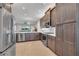 Modern kitchen features stainless steel appliances, wood cabinets and an open view to the living room at 4931 Sevilla Shores Dr, Wimauma, FL 33598