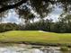 Scenic view of the lush golf course with mature trees, a pond, and a sand trap at 5132 Pinnacle Dr, Oldsmar, FL 34677