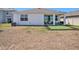 View of the back of the house with a small, covered patio and a small artificial turf area at 5464 Flint Hills Dr, Wimauma, FL 33598