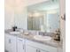 Bright main bathroom with double sinks, granite counters, and a large mirror at 5464 Flint Hills Dr, Wimauma, FL 33598