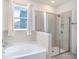 Bright bathroom featuring a soaking tub, a walk-in shower with glass doors, and a window at 5464 Flint Hills Dr, Wimauma, FL 33598