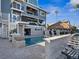 Backyard view of a multi-story home, pool, tiki bar, and outdoor seating area for relaxation and entertainment at 5820 Balao S Way, St Pete Beach, FL 33706