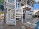 Exterior view of a spiral staircase connecting to multiple balconies, located next to the pool area at 5820 Balao S Way, St Pete Beach, FL 33706