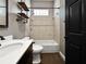 Cozy bathroom with white tile, dark wood vanity, shelves, and a black framed glass block window above the tub at 6994 Fort King Rd, Zephyrhills, FL 33541
