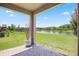 View from covered brick patio to green lawn, pond, and fence beyond at 9309 Tradewater Oaks Ct, Riverview, FL 33578
