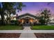 Charming bungalow at twilight with manicured lawn and beautiful landscaping, creating great curb appeal at 1001 S Oregon Ave, Tampa, FL 33606