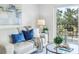 Comfortable living room with a plush white couch, blue pillows, and glass table next to a sliding glass door to balcony at 1120 N Shore Ne Dr # 201, St Petersburg, FL 33701