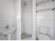 All-white bathroom featuring pedestal sink, tiled shower, and open shelving at 11625 5Th E St, Treasure Island, FL 33706