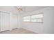 Bright bedroom featuring two shuttered-door closets, neutral tile floors, and a window at 11625 5Th E St, Treasure Island, FL 33706