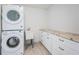Bright laundry room with stacked washer and dryer, a utility sink, granite counters and ample storage at 11625 5Th E St, Treasure Island, FL 33706