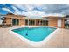 Backyard view of in-ground pool surrounded by tile patio and light orange single story home with multiple glass sliding doors at 11625 5Th E St, Treasure Island, FL 33706