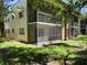 Condominium building with screened-in balconies, surrounded by lush landscaping and a well-maintained lawn at 11807 Raintree Lake Ln # B, Tampa, FL 33617