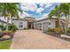 Beautiful home exterior featuring a three-car garage, brick driveway, and lush landscaping at 13208 Malachite Dr, Bradenton, FL 34211
