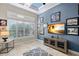 Living room with blue accent wall, plantation shutters, TV, console and tiled floor at 13208 Malachite Dr, Bradenton, FL 34211