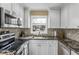 Bright kitchen features granite countertops, white cabinets, stainless steel appliances, and modern tile backsplash at 13696 Orange Sunset Dr, Tampa, FL 33618