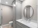 Bathroom featuring gray vanity with white countertop, round mirror, and storage cabinet at 13704 Evelane Dr, Hudson, FL 34667